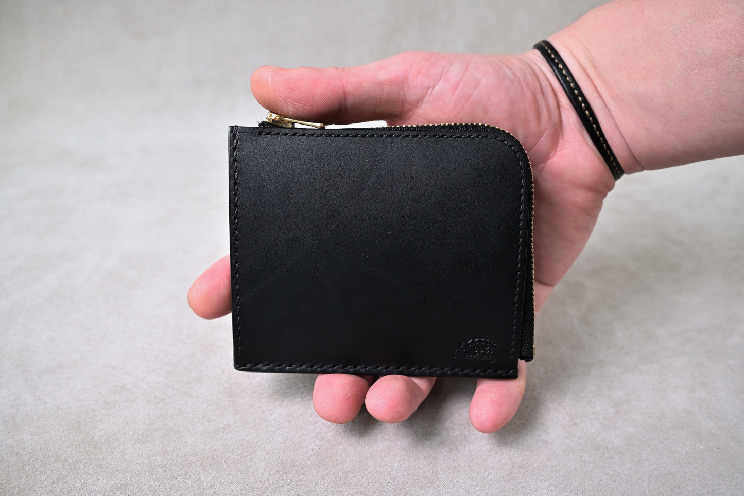 ブッテーロブラックのハーフウォレットを手に持った構図で撮影(サイズ感と質感が直感的に伝わる)