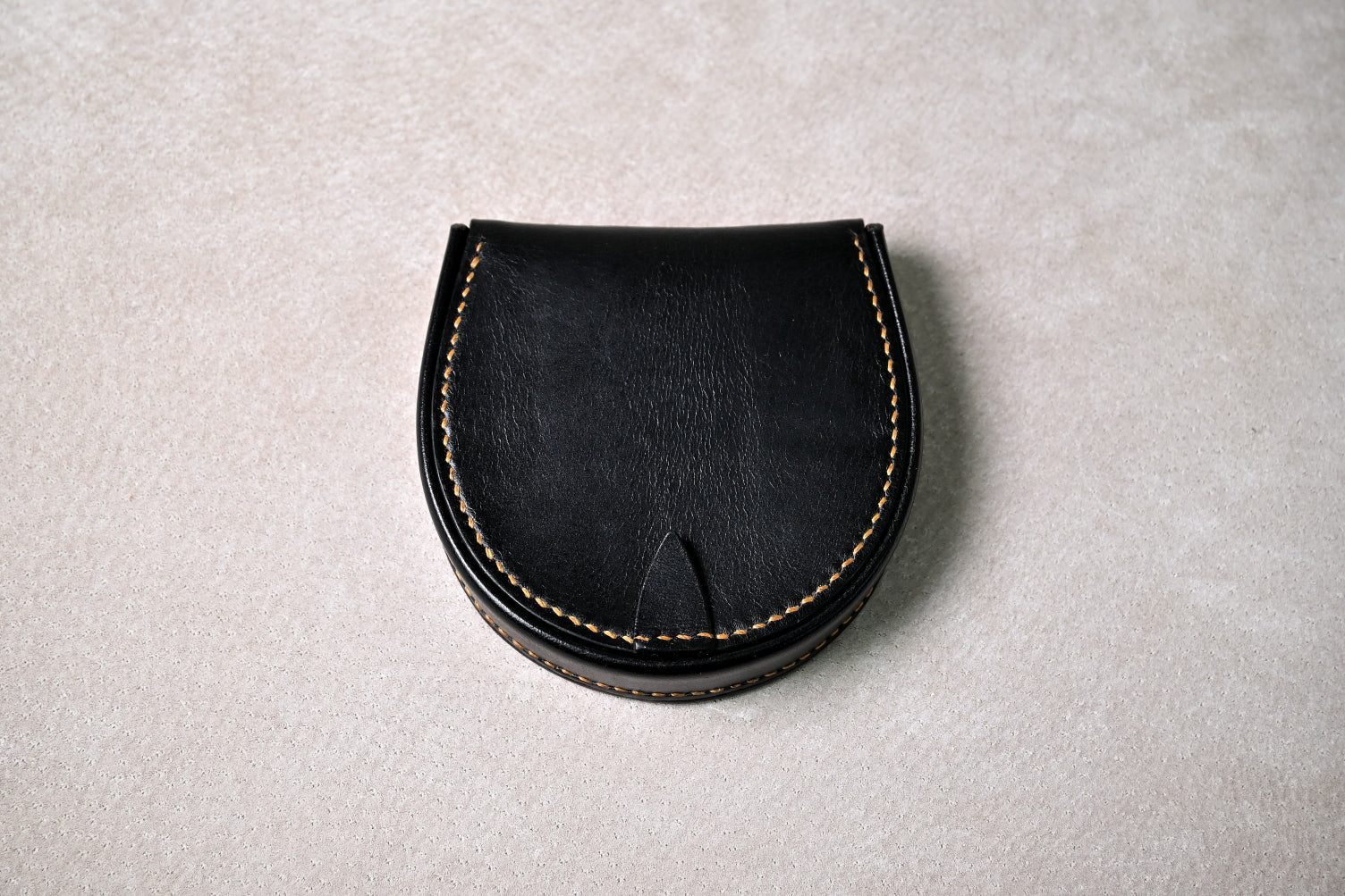 ブッテーロのブラックの馬蹄型コインケース「shihu」を真上から撮影（閉じた状態、滑らかなカーブと縫製ラインが際立つ）