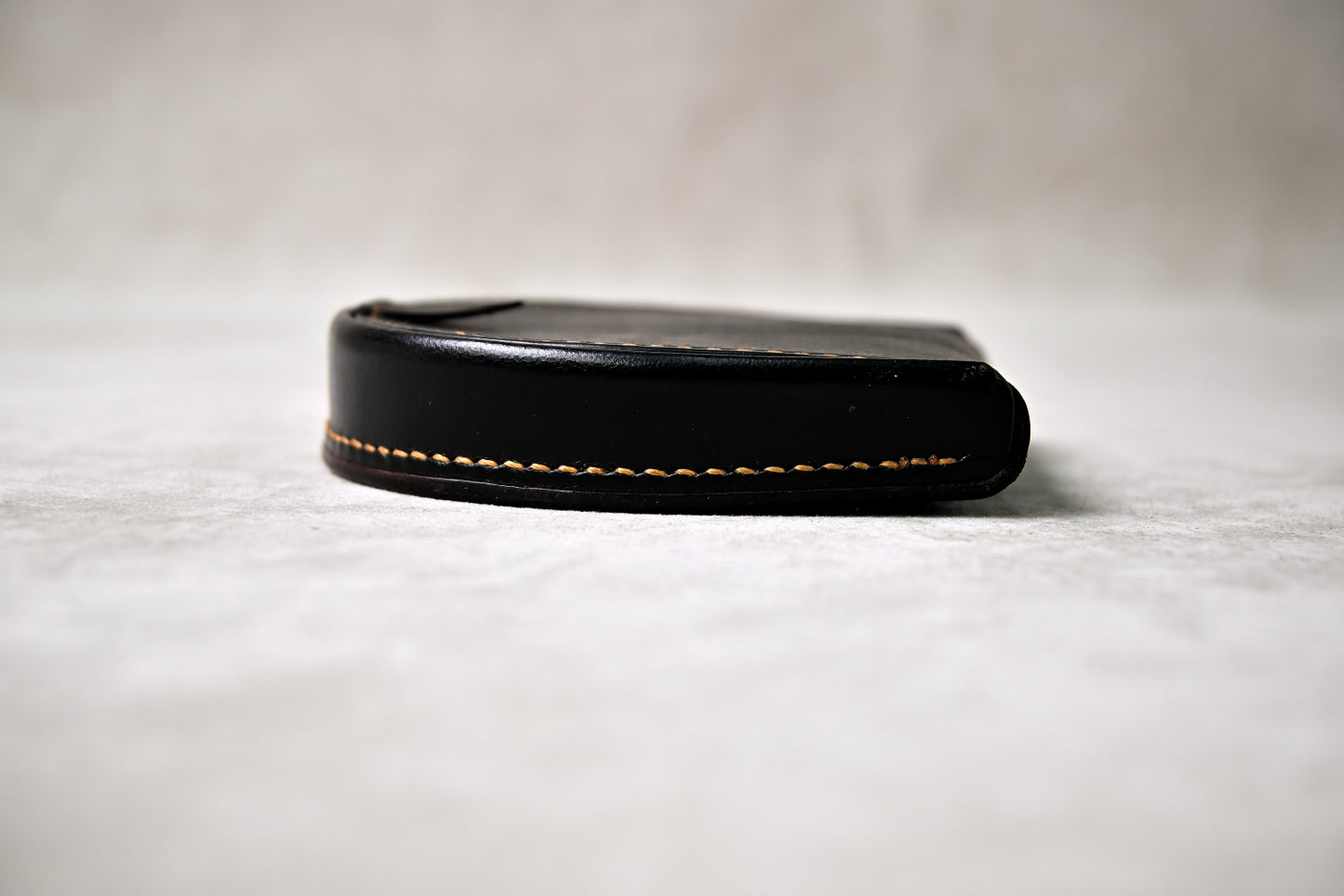 ブッテーロのブラックの馬蹄型コインケースを横から撮影（厚みと麦色ステッチが際立つ構図）
