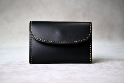 ブッテーロのブラックとキャメルで仕立てたホック留めコインケースを正面から撮影（手縫い、麦色ステッチ）