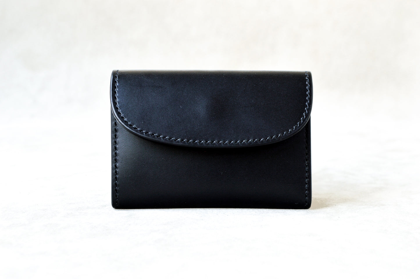 ブッテーロのブラックで仕立てたTetoコインケースを正面から撮影（内装もブラック、シックな統一感、手縫い）
