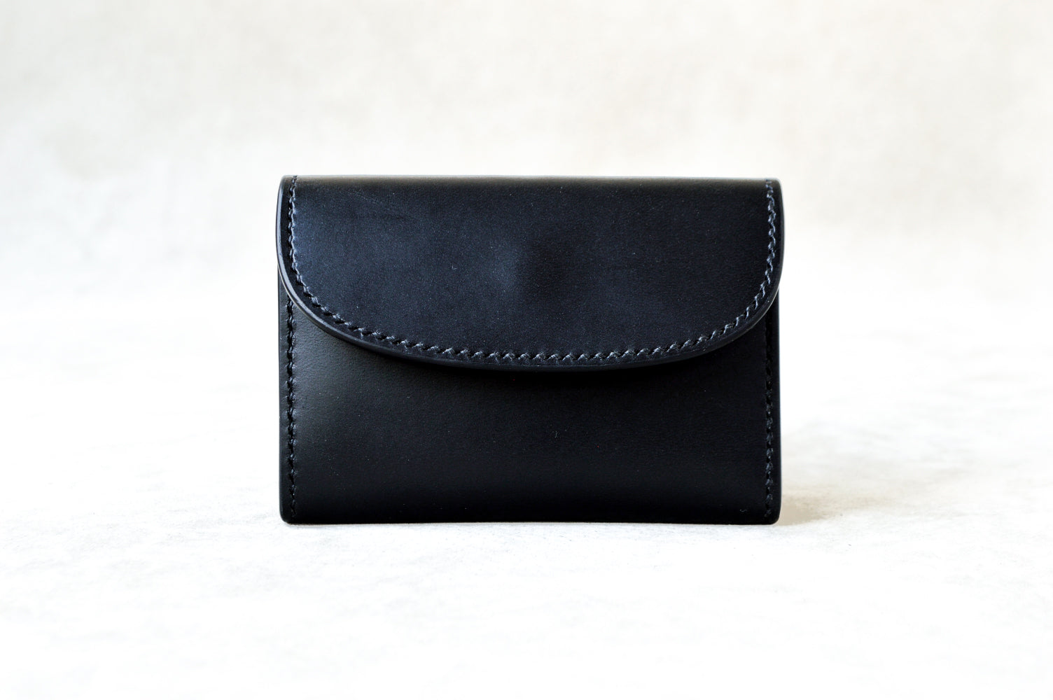 ブッテーロのブラックで仕立てたTetoコインケースを正面から撮影（内装もブラック、シックな統一感、手縫い）