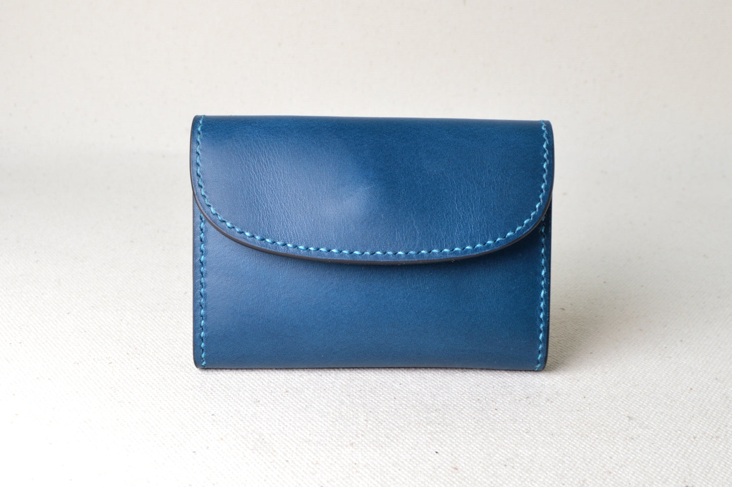 ブッテーロのブルーとナチュラルで仕立てたTetoコインケースを正面から撮影（明るく爽やかな配色、手縫い）