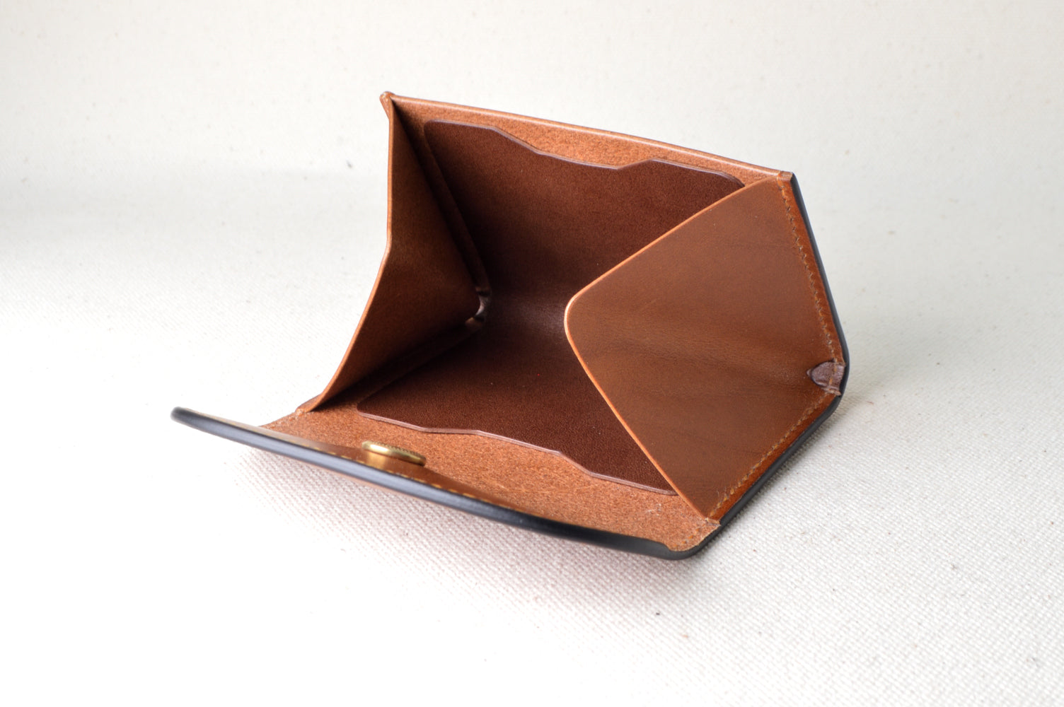 キャメル外装・ブラウン内装にオレンジの仕切りが入ったコインケースを開いた状態で撮影（多色構成、手縫い）