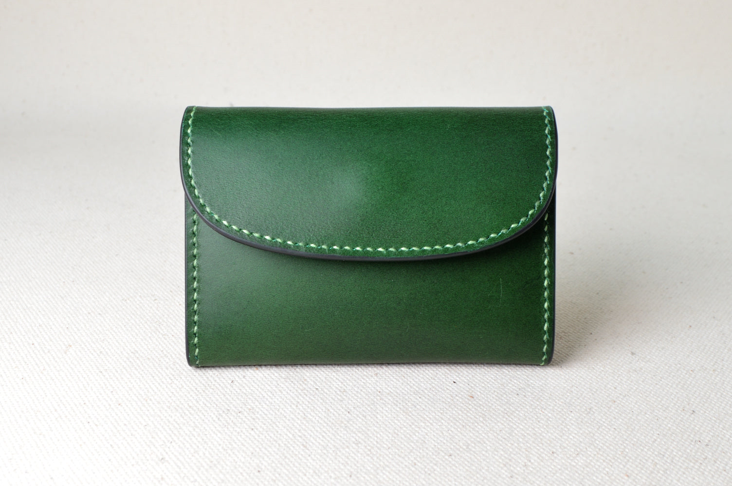 ブッテーロのグリーンとキャメルで仕立てたTetoコインケースを正面から撮影（ライトグリーンの糸、手縫い、爽やかな配色）