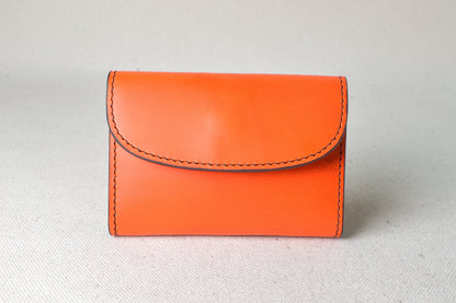 ブッテーロのオレンジ外装にブラウン内装を合わせたTetoコインケースを正面から撮影（温かみある色合い、手縫い）