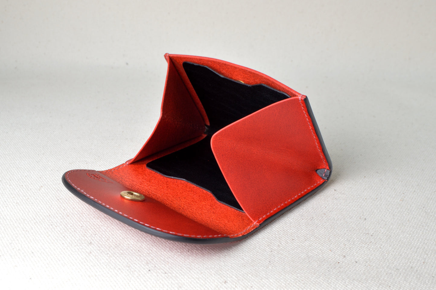 レッド×ブラック×ピンクの内装が見えるホック式コインケースを開いた状態で撮影（立体感と色のコントラスト）