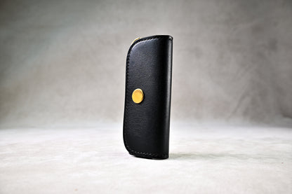 ブッテーロのブラックで仕立てたキーケースを立てかけて撮影（真鍮ホック、シンプルな外装）