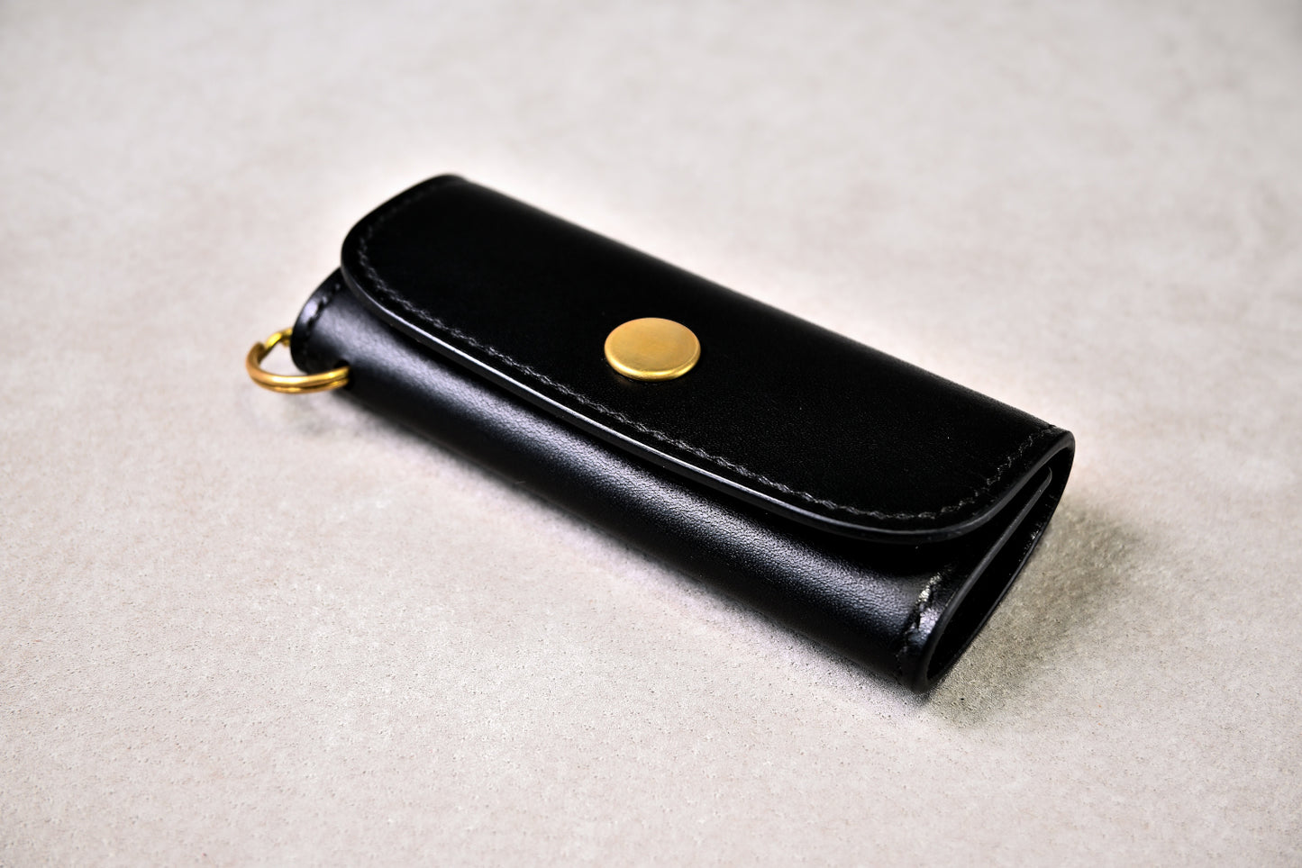 真鍮金具が映えるブッテーロブラックのキーケースを斜め上から撮影（手縫い、立体感）