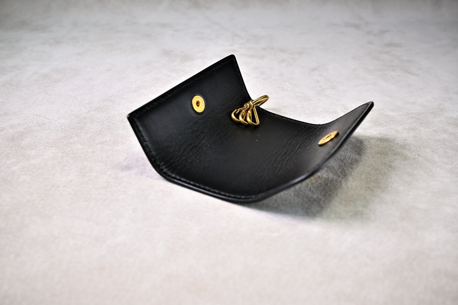 ブッテーロブラックのキーケースを開いて真上から撮影（真鍮製キーフック付き、仕立ての丁寧さ）