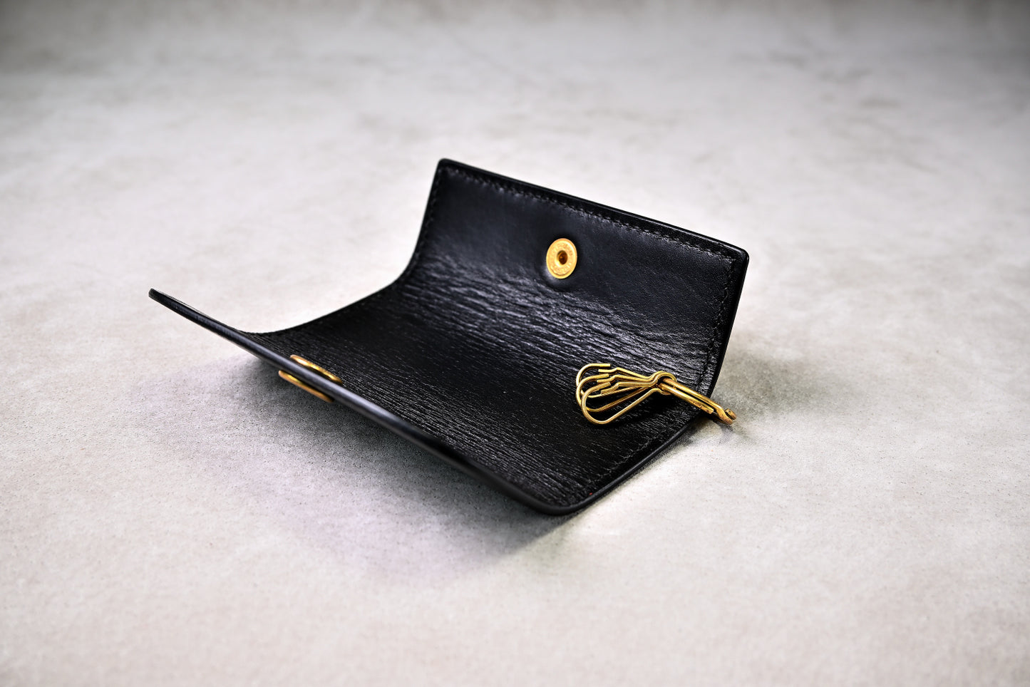 キーフックが見える開いた状態のキーケースを斜めから撮影（真鍮パーツ、革の艶感）