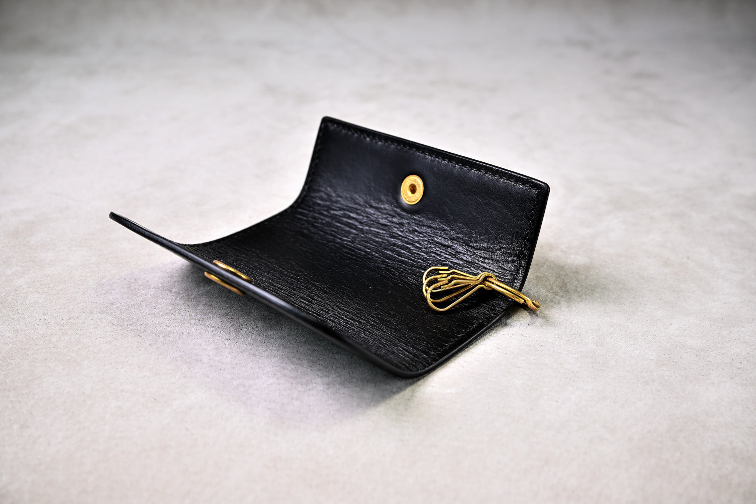 キーフックが見える開いた状態のキーケースを斜めから撮影（真鍮パーツ、革の艶感）