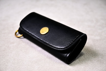 ブッテーロブラックのキーケースを平置きで撮影（真鍮ホック、丸みのある縁仕立て）